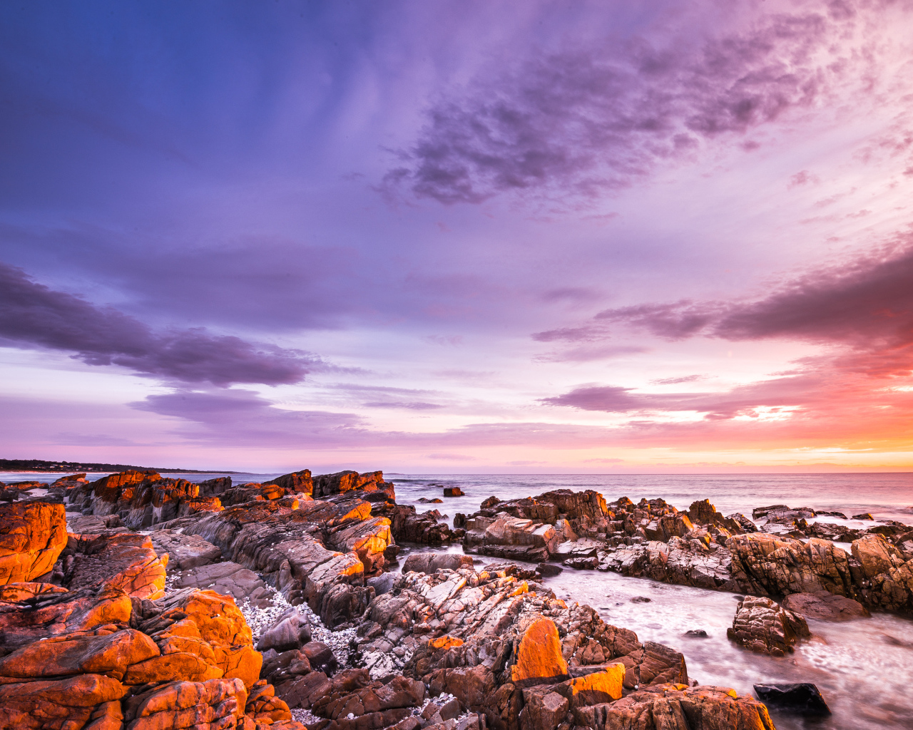 Каменный берег в море на закате солнца