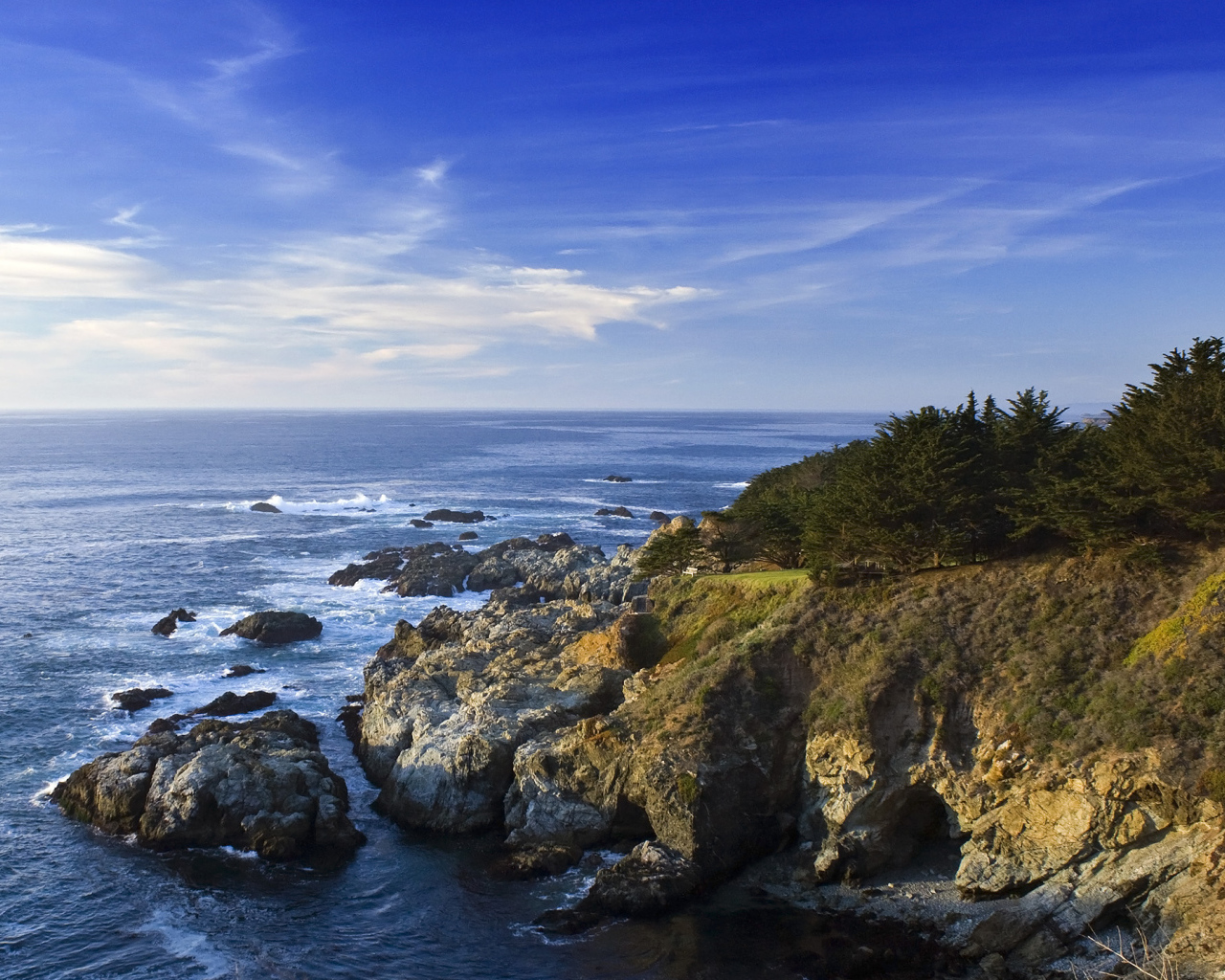 Каменные скалы береговой линии в океане под голубым небом