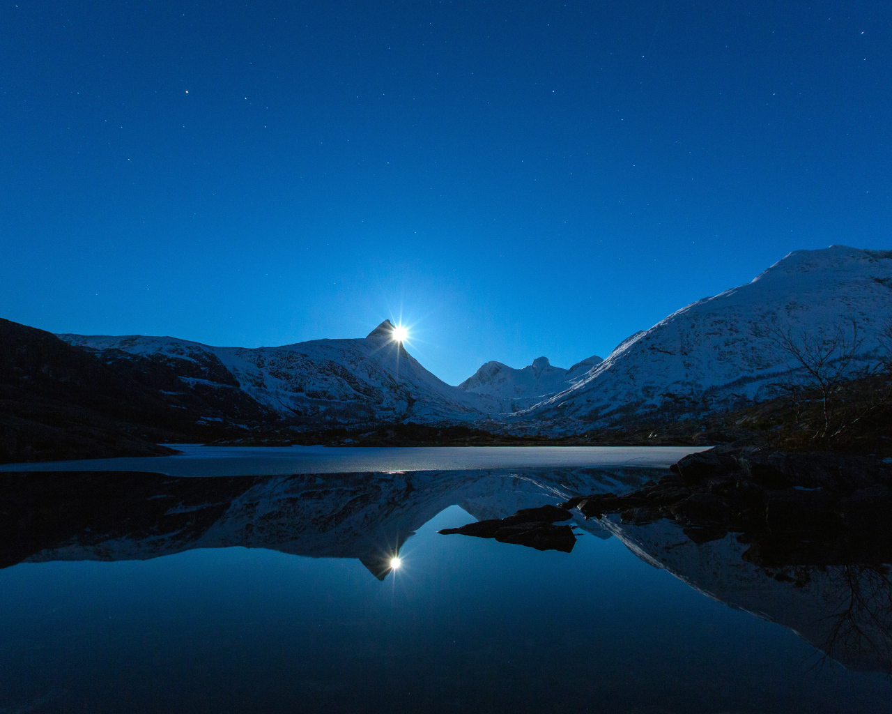 Луна и заснеженные горы отражаются в воде 