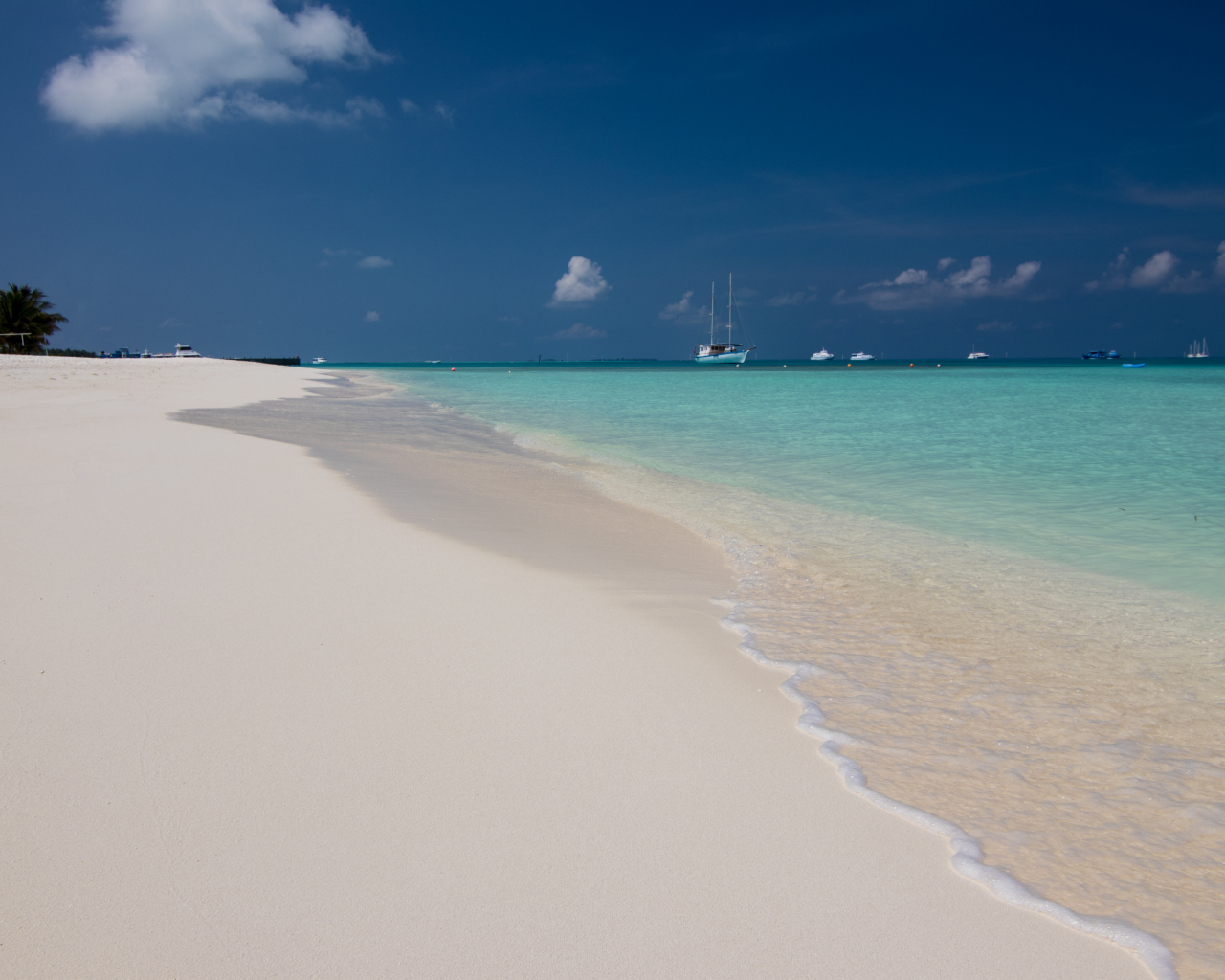 Спокойные волны на белом горячем песке под голубым небом