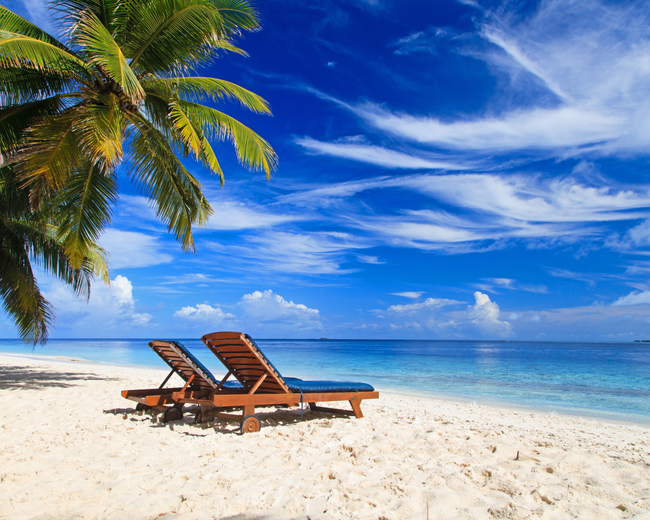 Шезлонги на тропическом пляже под голубым небом
