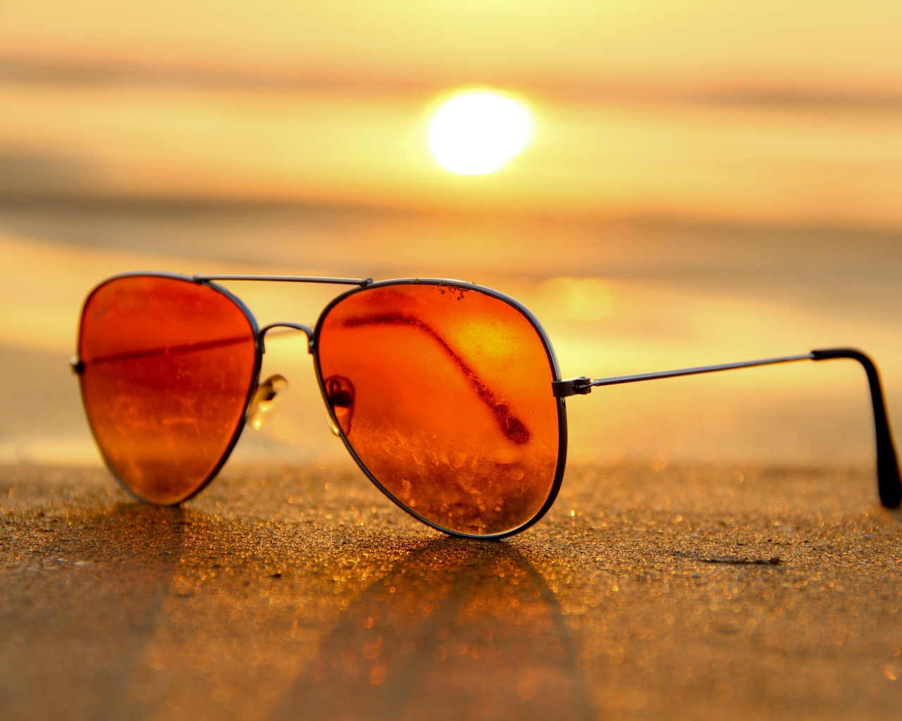 Солнечные очки лежат на горячем морском песке