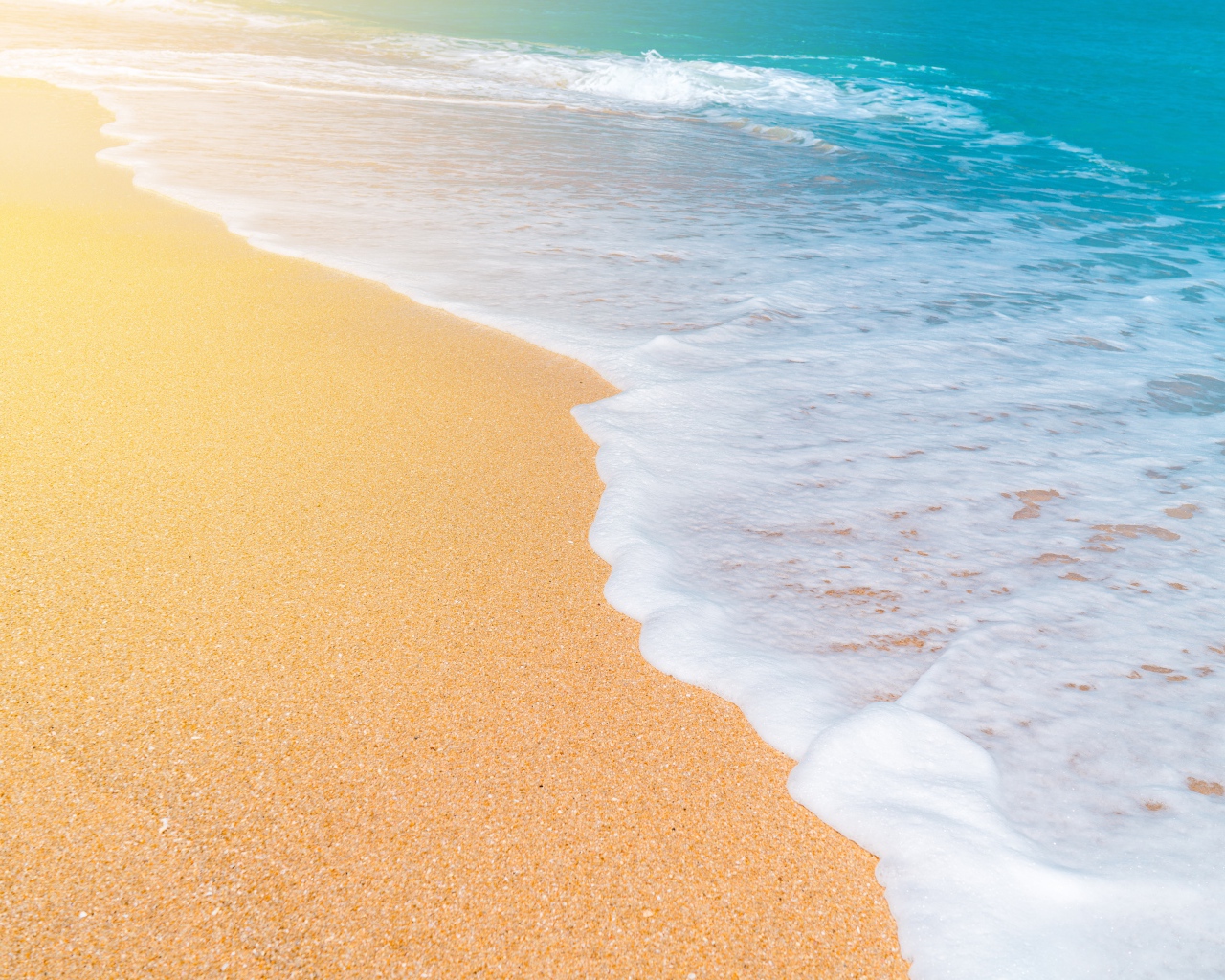 Белые волны океана омывают желтый горячий песок на пляже
