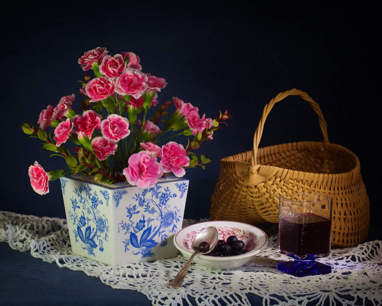 Букет гвоздик в красивой вазе на столе с корзиной и соком