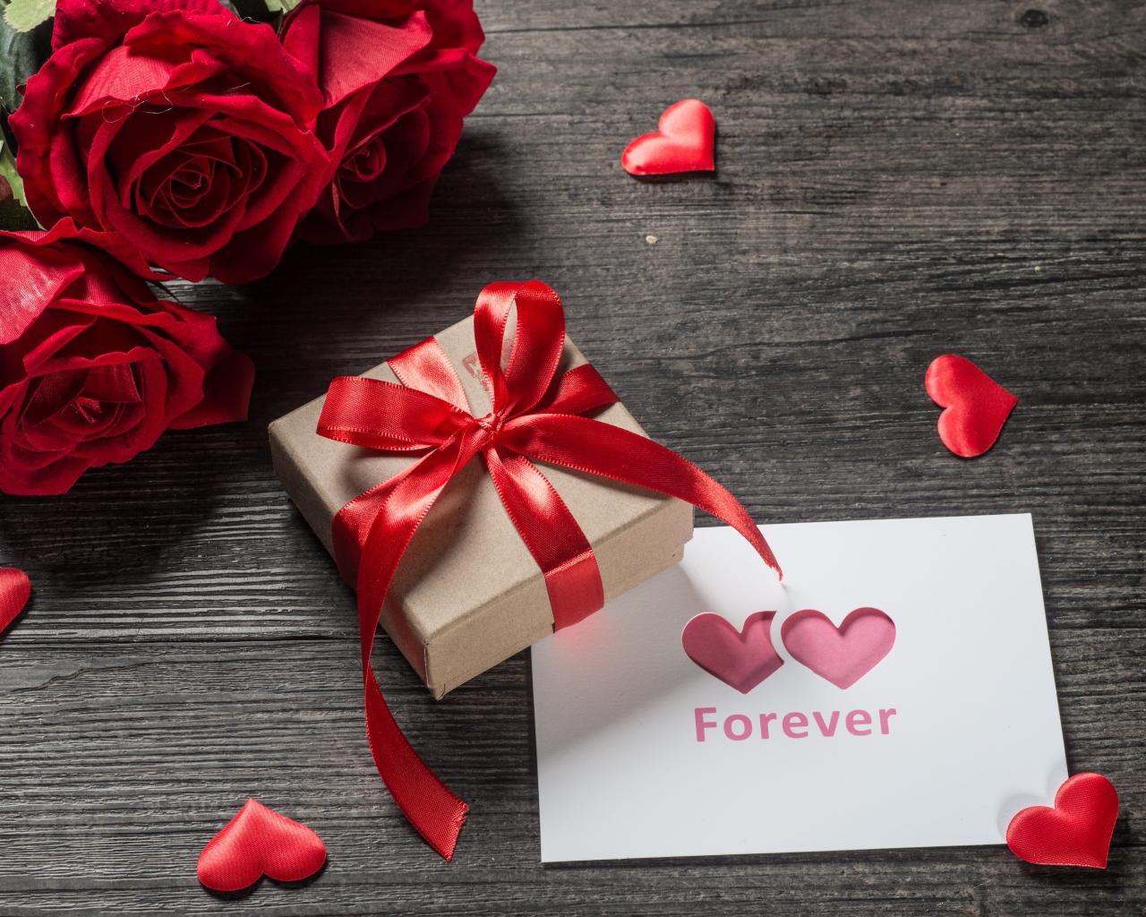Букет красных роз с подарком и открыткой на столе