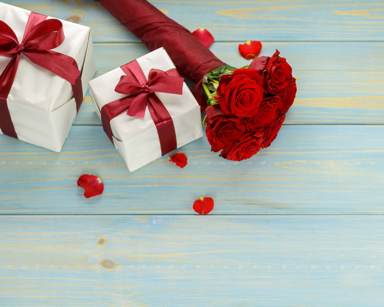 Букет красных роз с подарками на столе