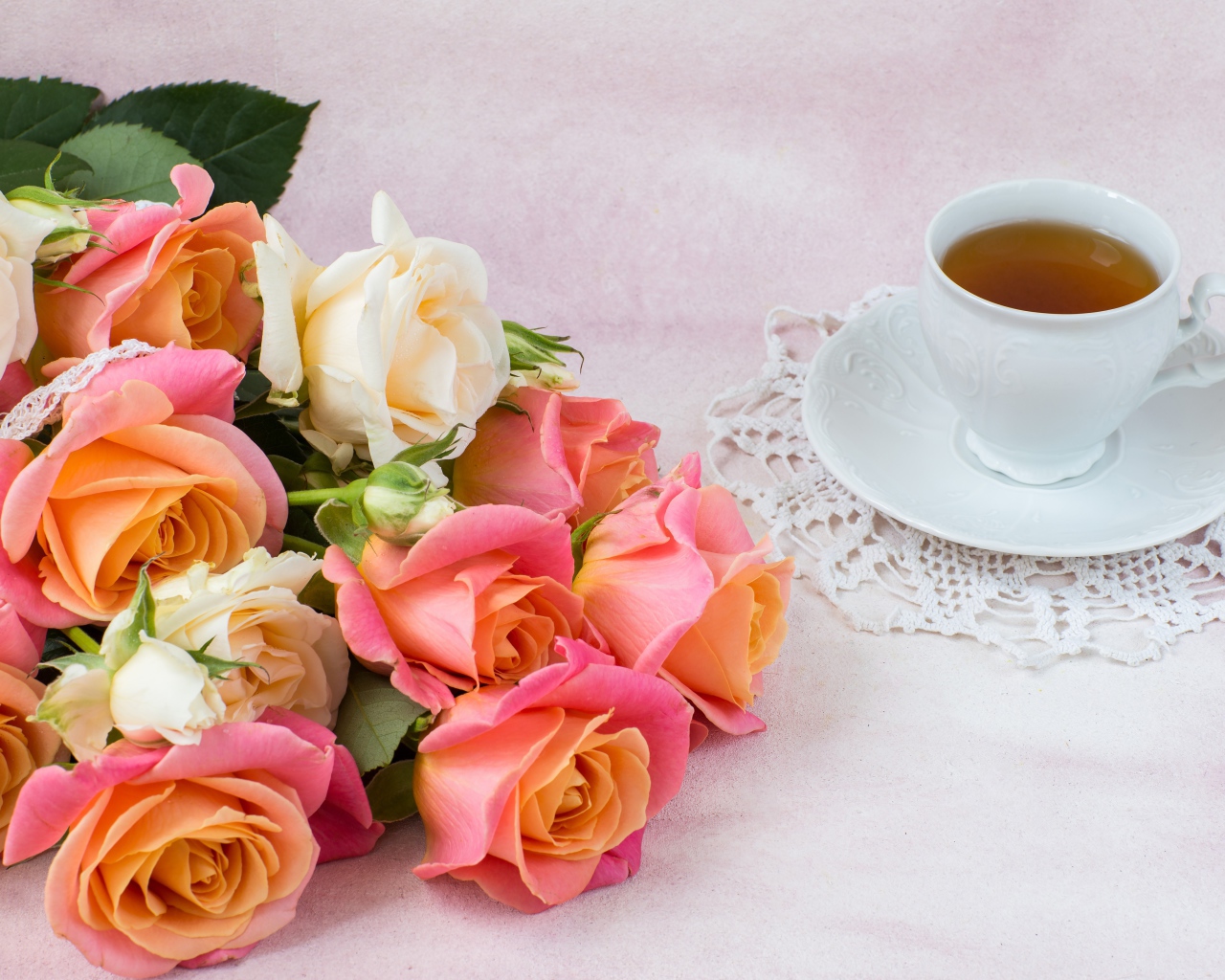Красивый букет нежных роз на столе с чашкой чая