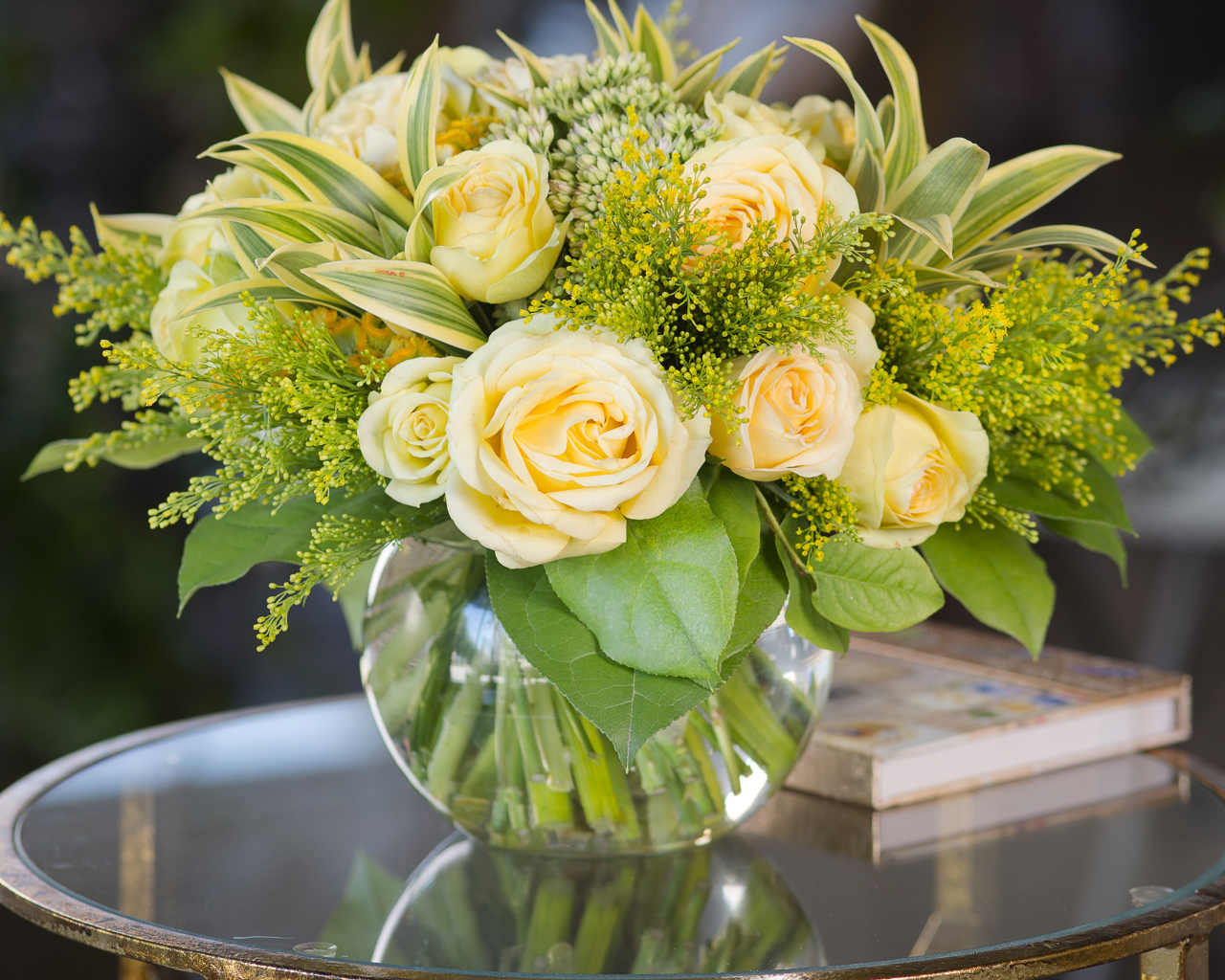 Красивый букет роз с зелеными листьями в в вазе на стеклянном столе