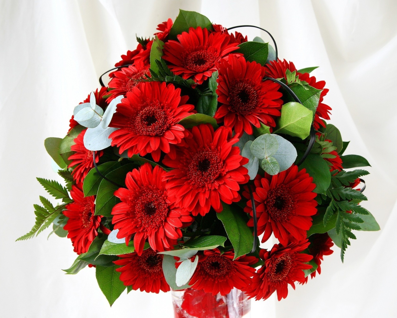 Красивый букет с красными герберами и зелеными листьями 