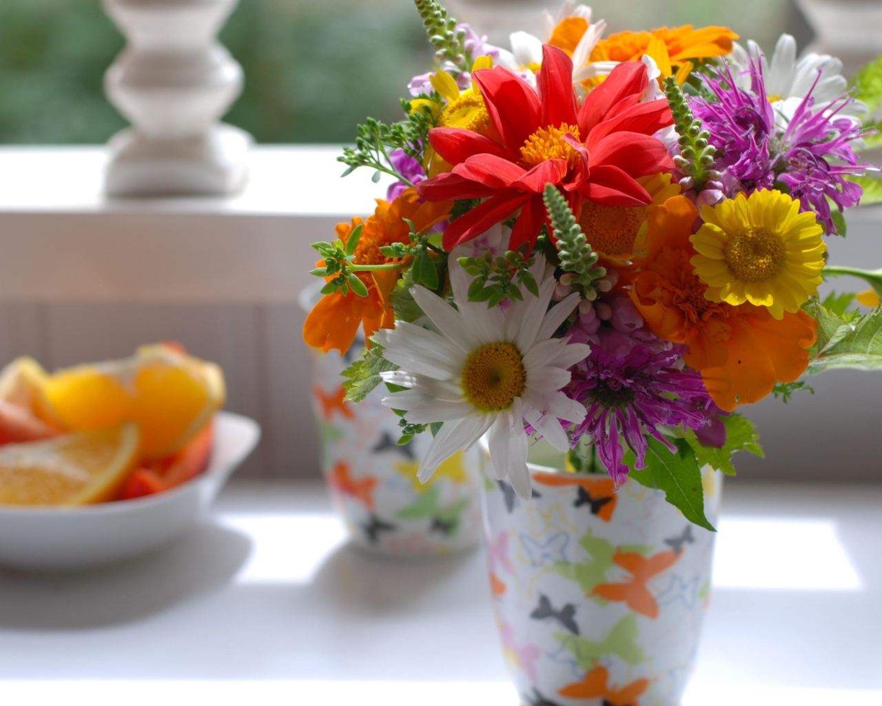 Букет разноцветных  садовых цветов в вазе на столе 