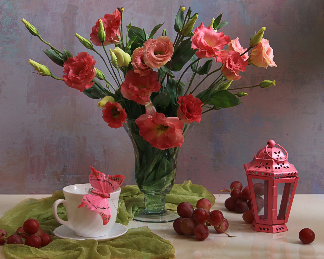 Букет розовых цветов эустомы на столе с виноградом