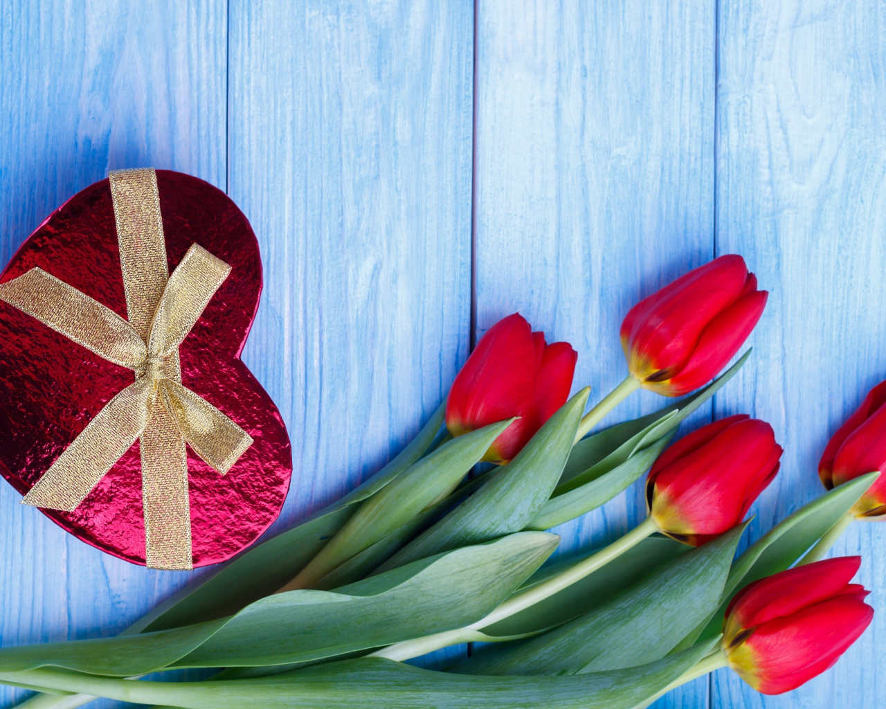 Букет красных тюльпанов на синем фоне с подарком в форме сердца