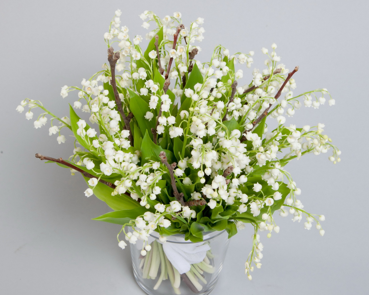 Букет белых ландышей в вазе на сером фоне