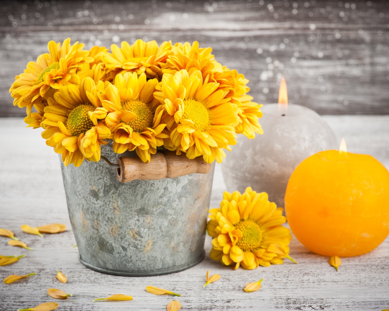 Букет желтых хризантем в ведерке на столе со свечами