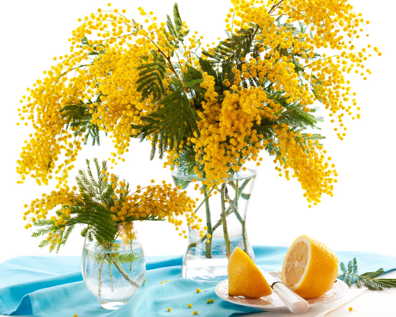 Букет желтой мимозы в вазе на столе с лимоном