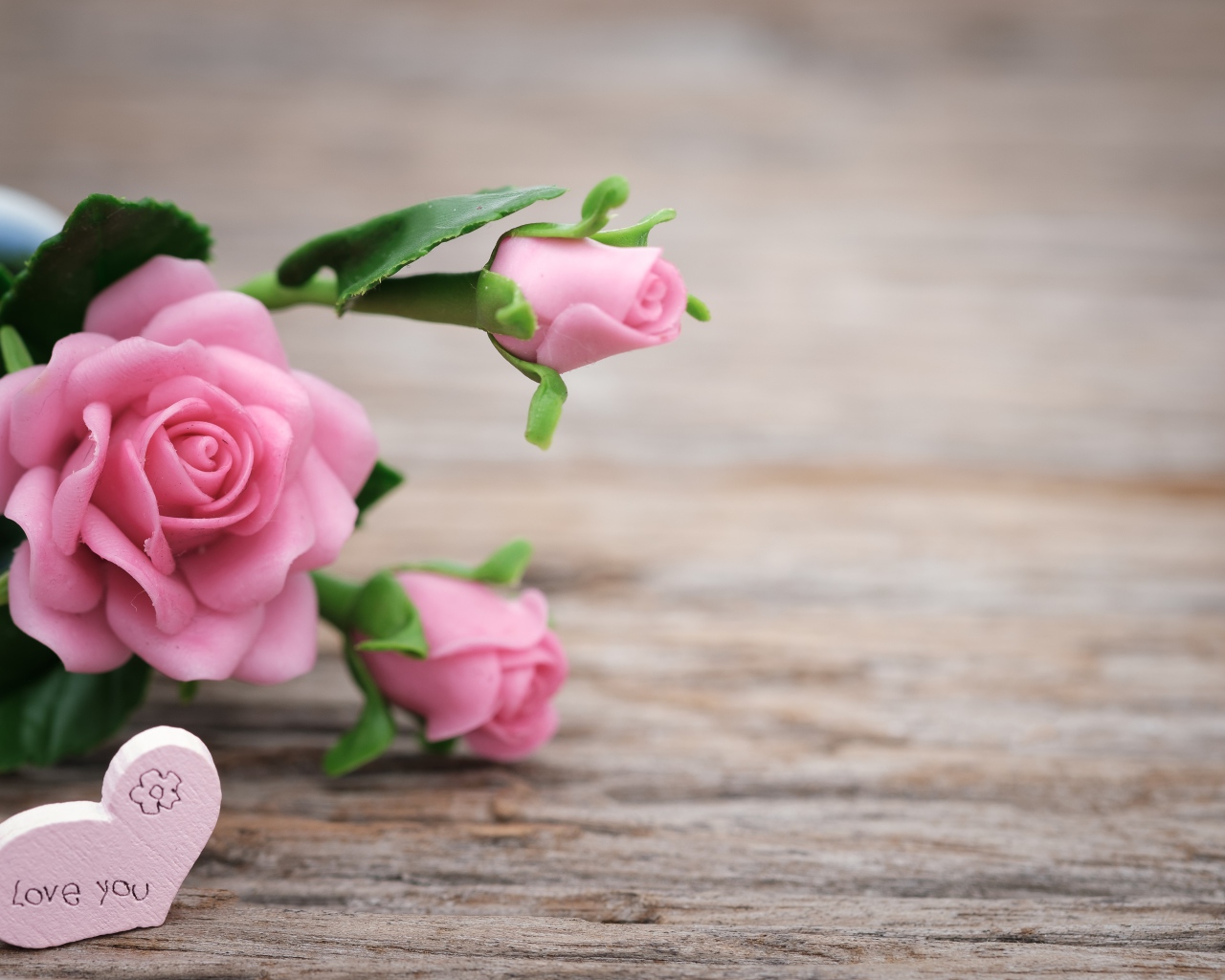 Розовые искусственные розы с сердцем на деревянном фоне