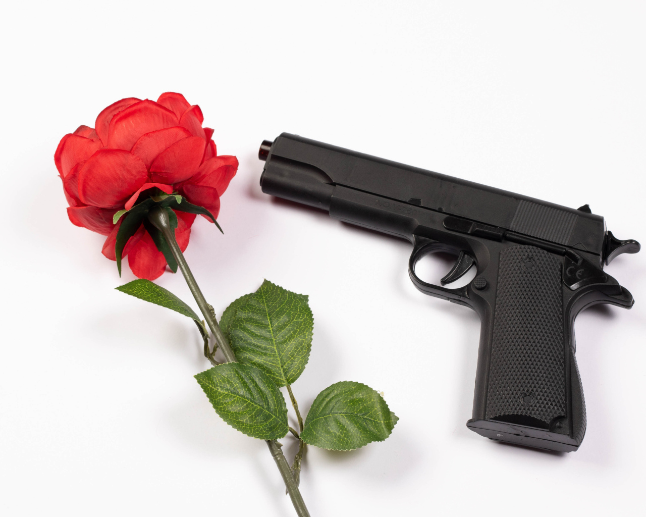 Красная роза и черный пистолет на белом фоне