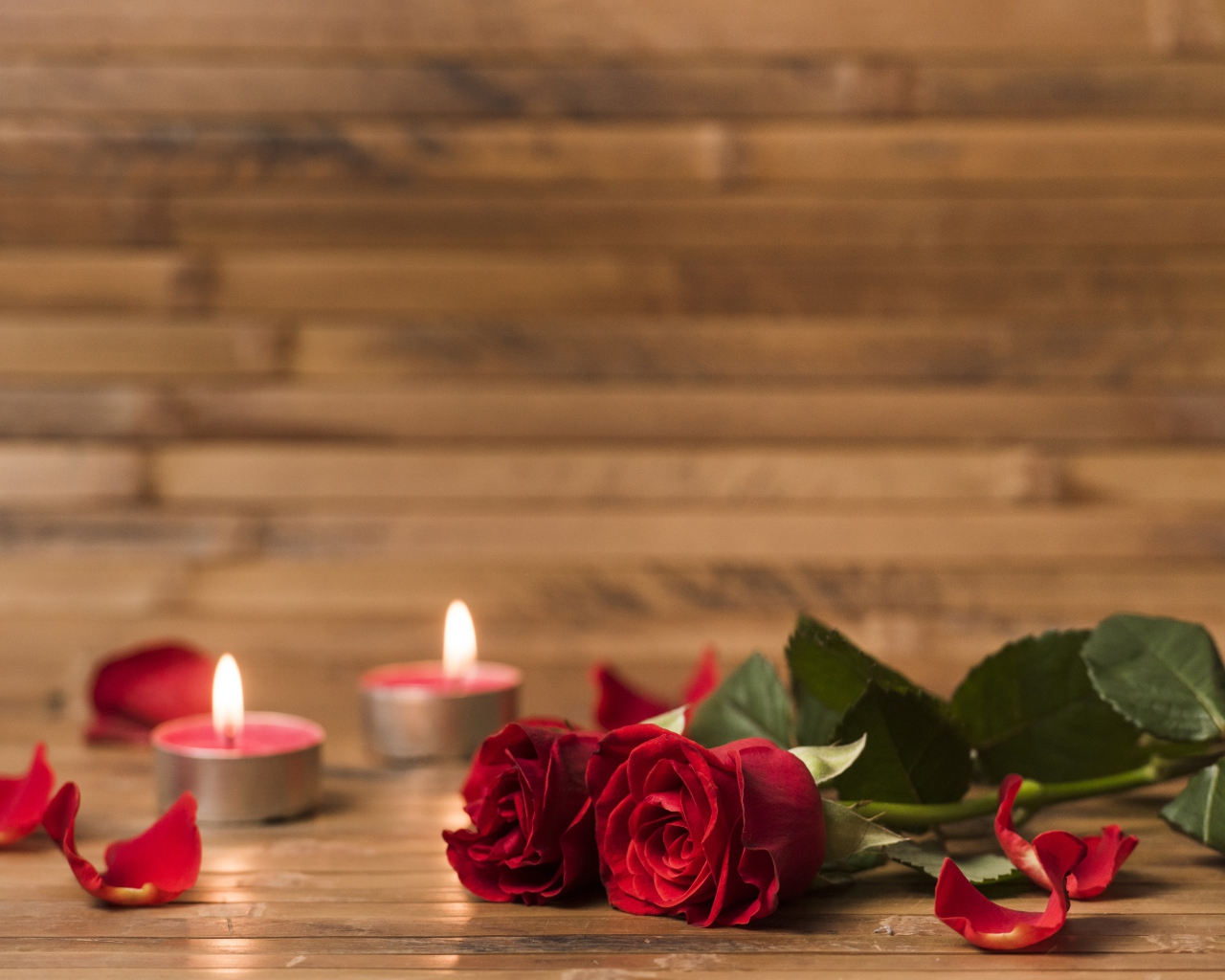 Две красные розы на столе с зажженными свечами 