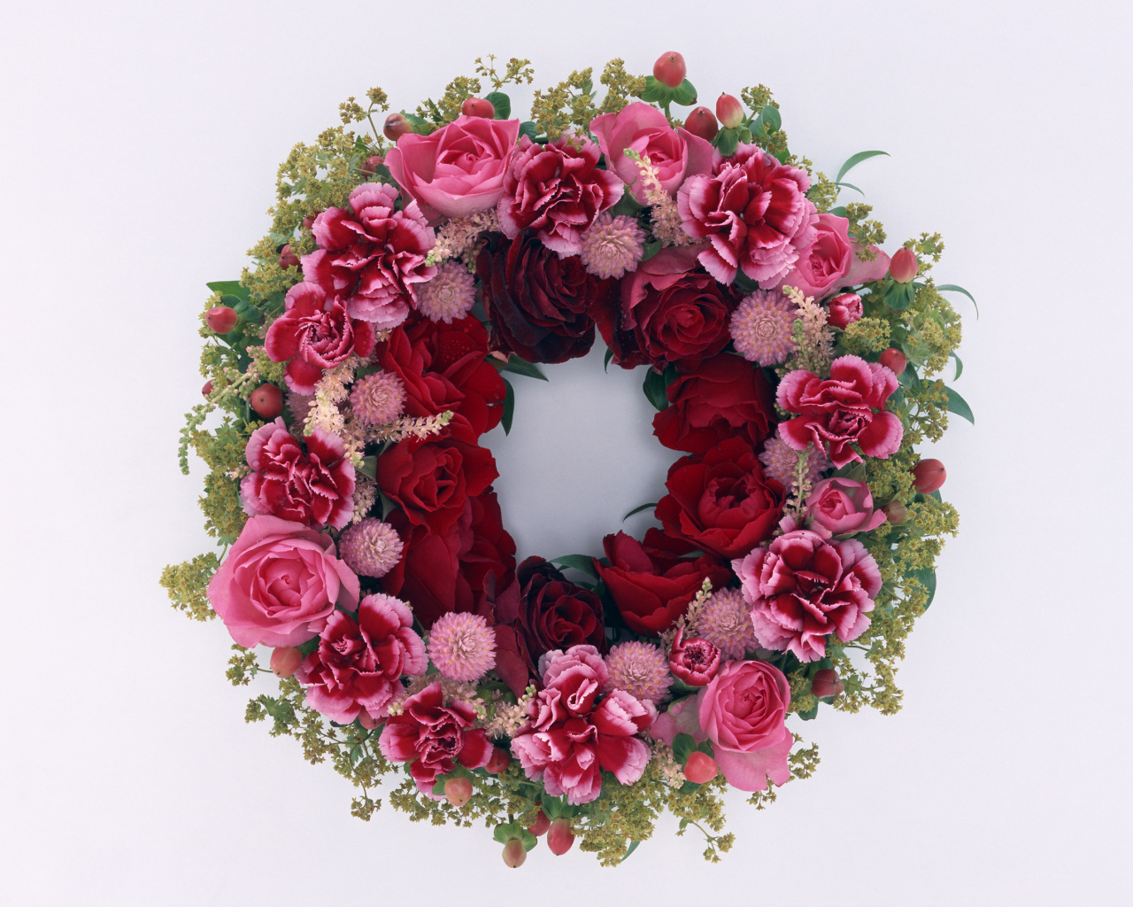 Венок и красных роз с цветами гвоздики на сером фоне