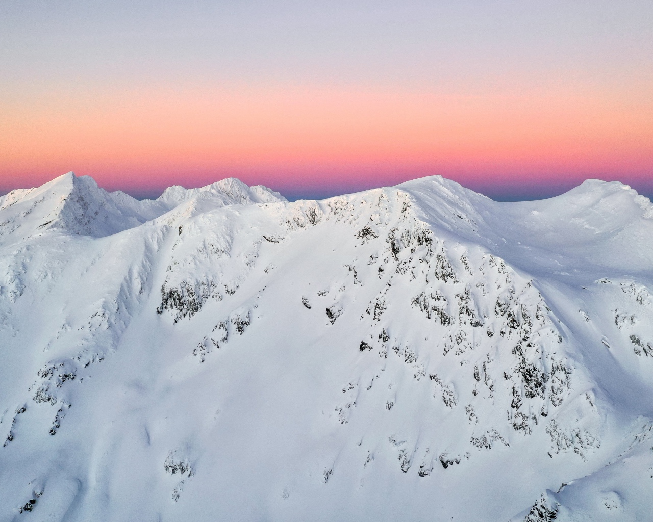 Красивые заснеженные вершины горы на фоне розового неба