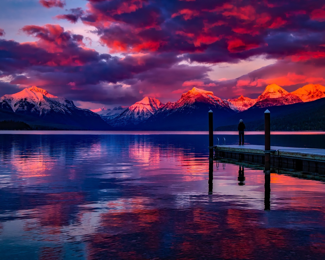 Красивый закат в небе над вершинами заснеженных гор у озера