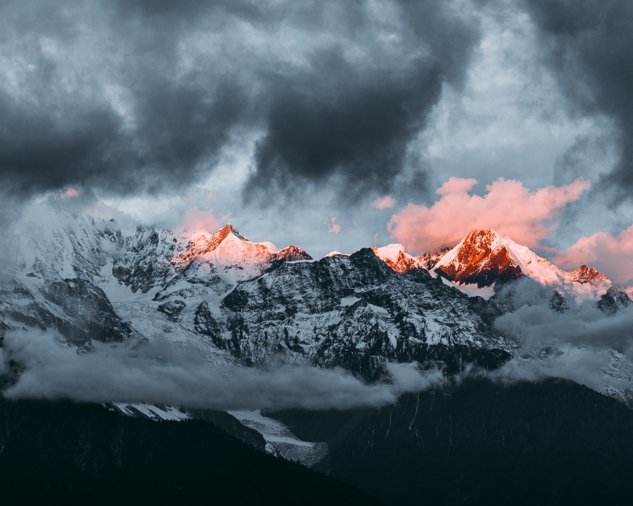 Солнце на рассвете освещает вершины заснеженных гор 