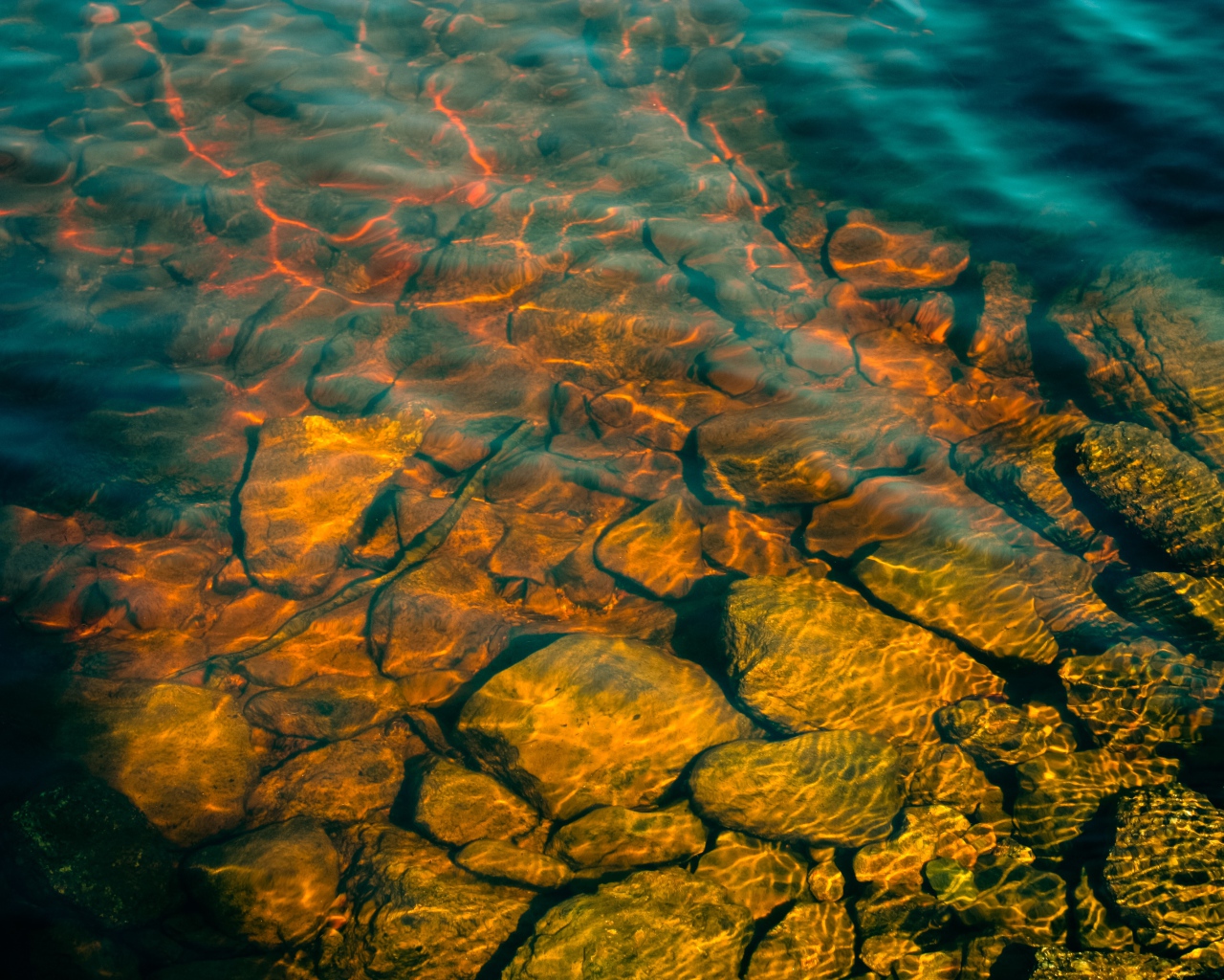 Камни на дне озера с чистой водой в лучах солнца