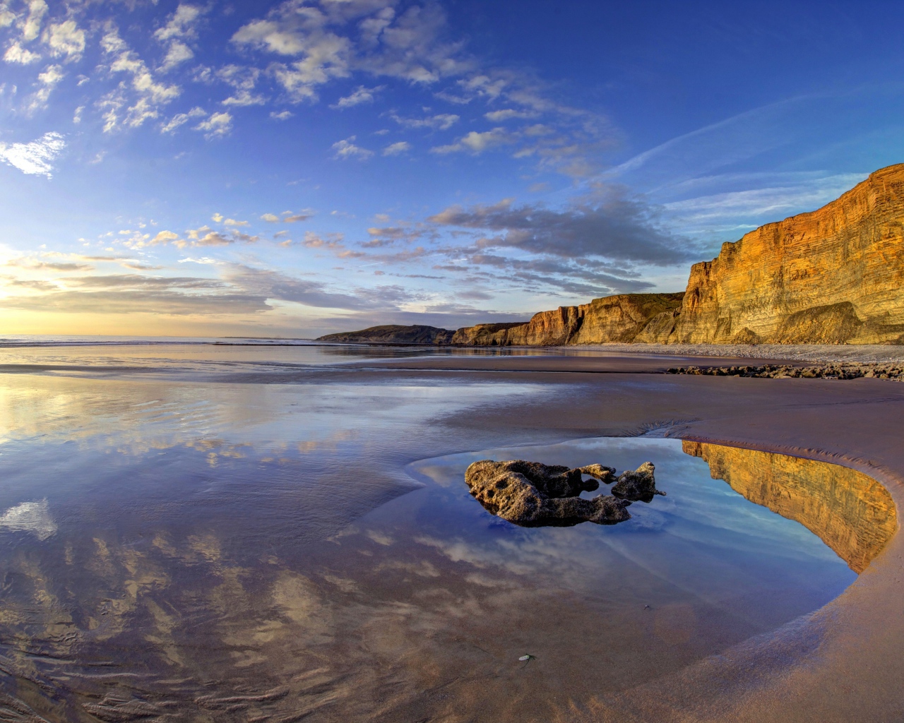 Мокрый морской берег со скалами на закате