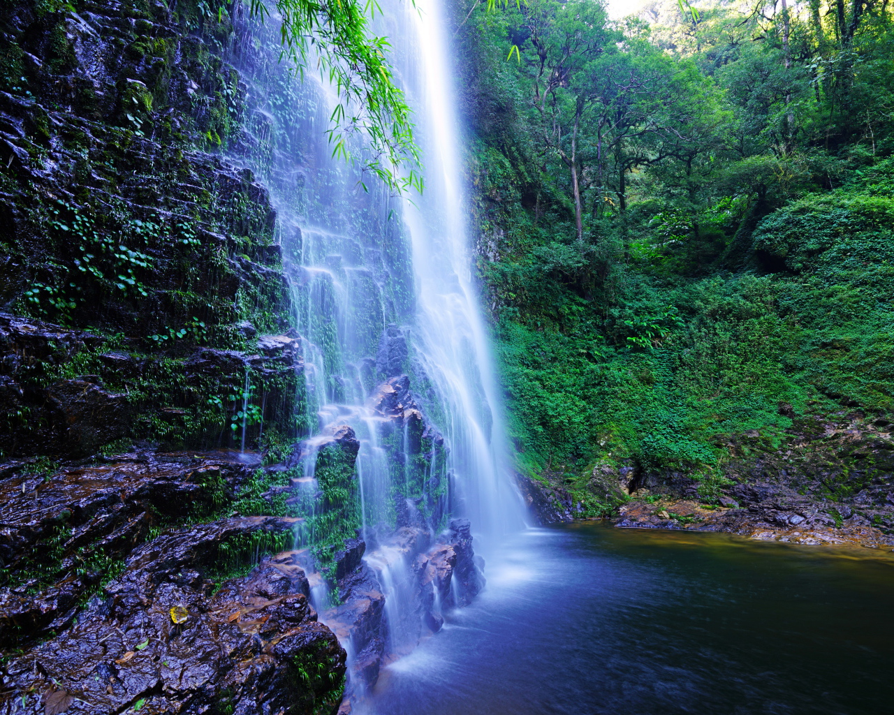 Быстрый водопад стекает по мокрым камням со скалы