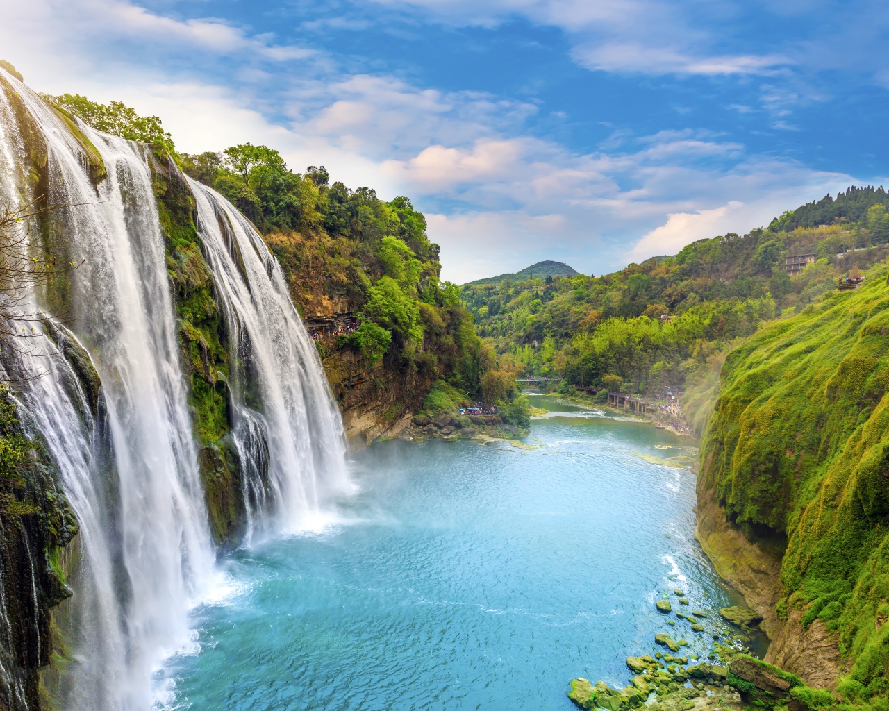 Быстрый водопад стекает с зеленых гор в реку