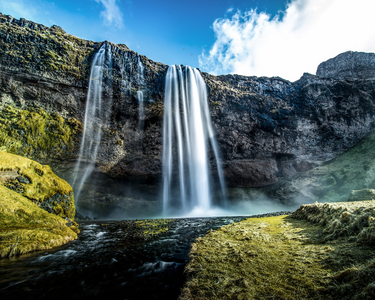 Водопад стекает с гор на фоне голубого неба
