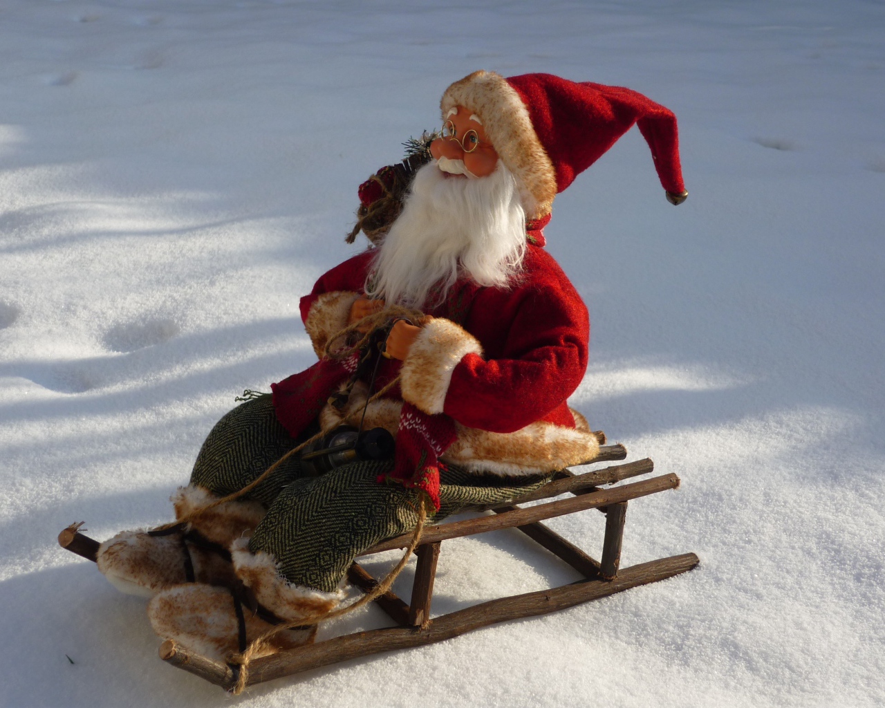 Игрушка деда Мороза на санках стоит на снегу