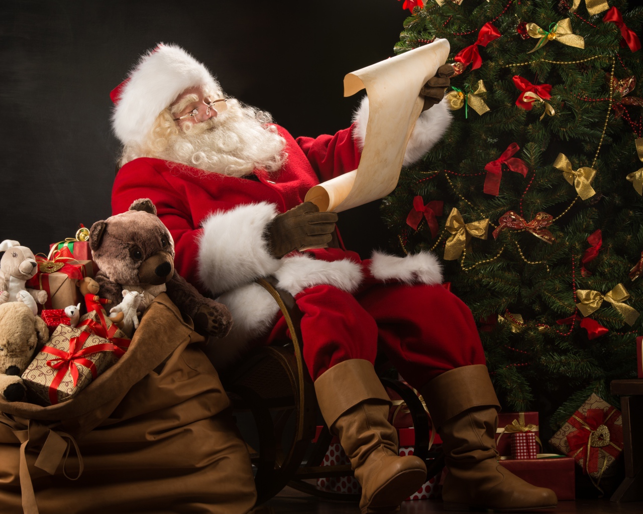 Санта Клаус с мешком подарков читает у елки