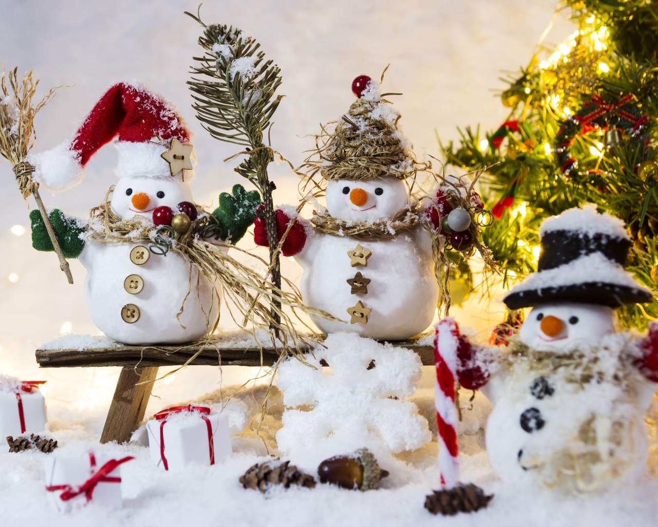 Три снеговика на снегу у искусственной елки на Новый год 