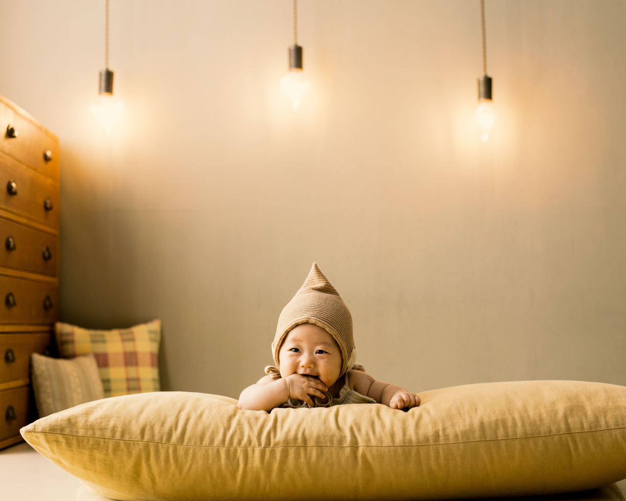 Маленький ребенок лежит на подушке под лампами
