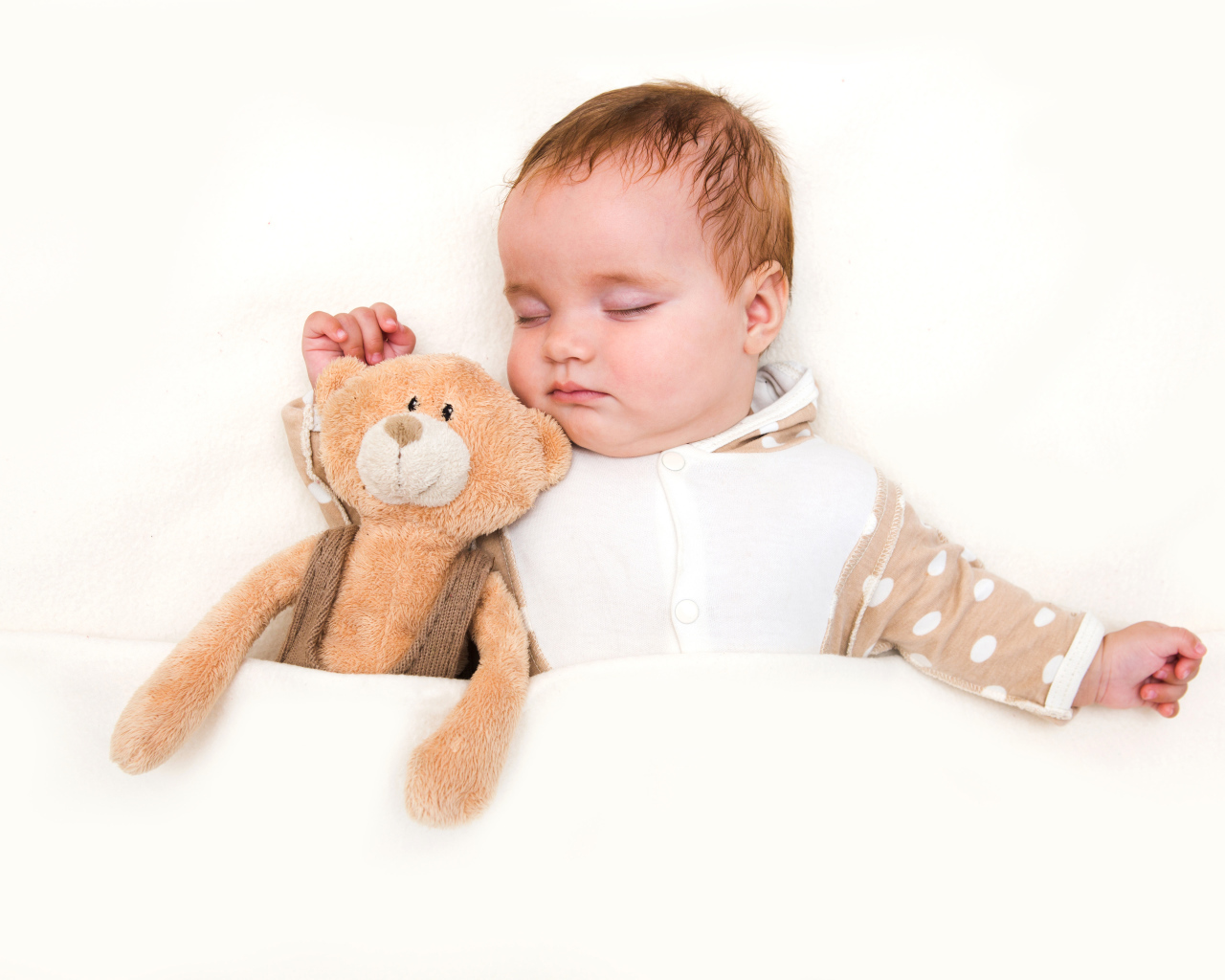 Грудной ребенок спит с плюшевым мишкой на белом фоне