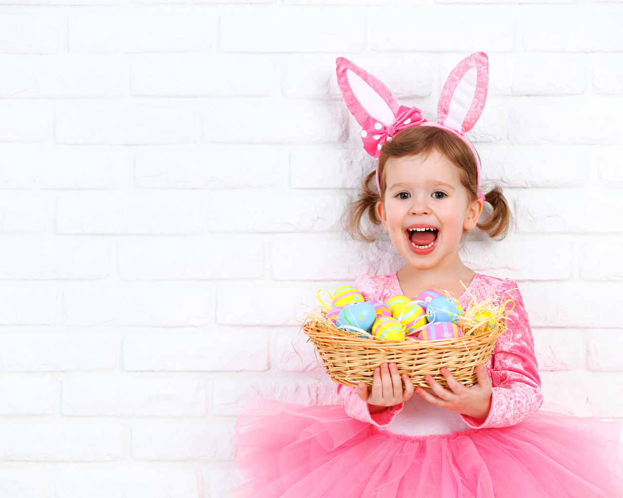 Красивая маленькая девочка в костюме с корзиной крашеных яиц 