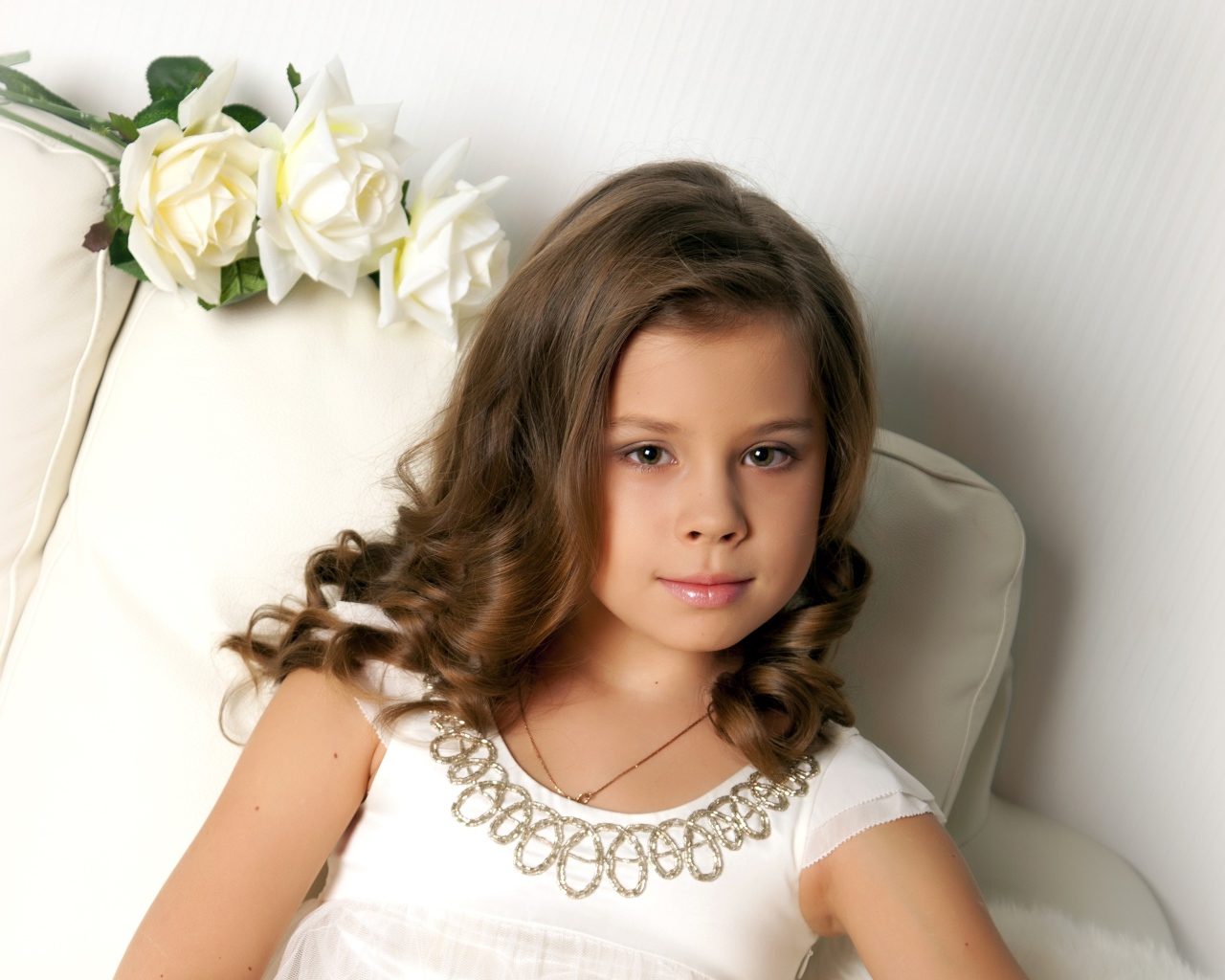 Красивая маленькая девочка сидит в кресле