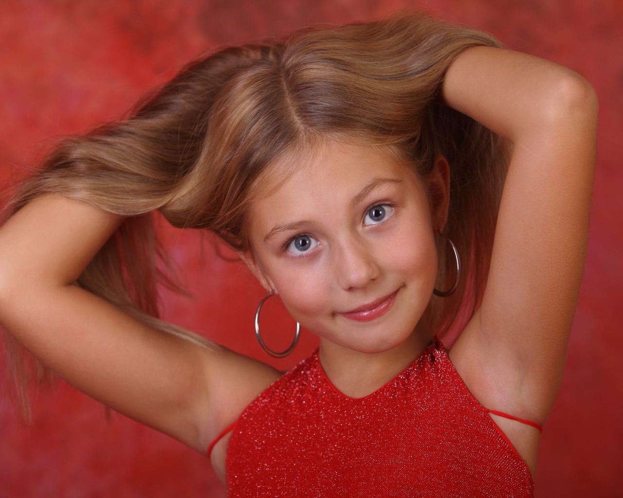 Красивая маленькая девочка с руками в волосах