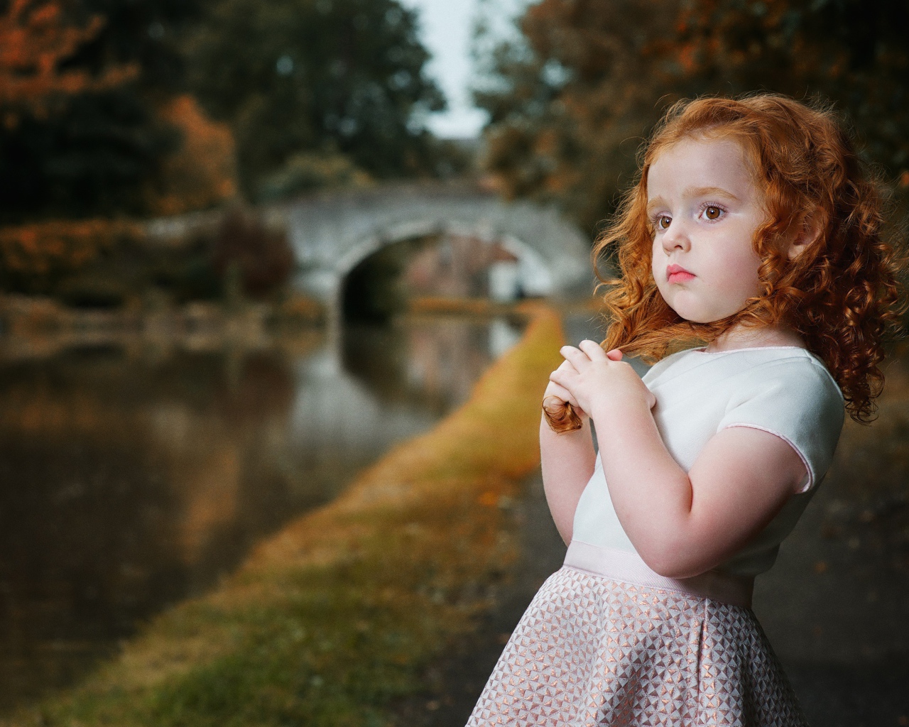 Красивая рыжеволосая девочка у реки в парке 