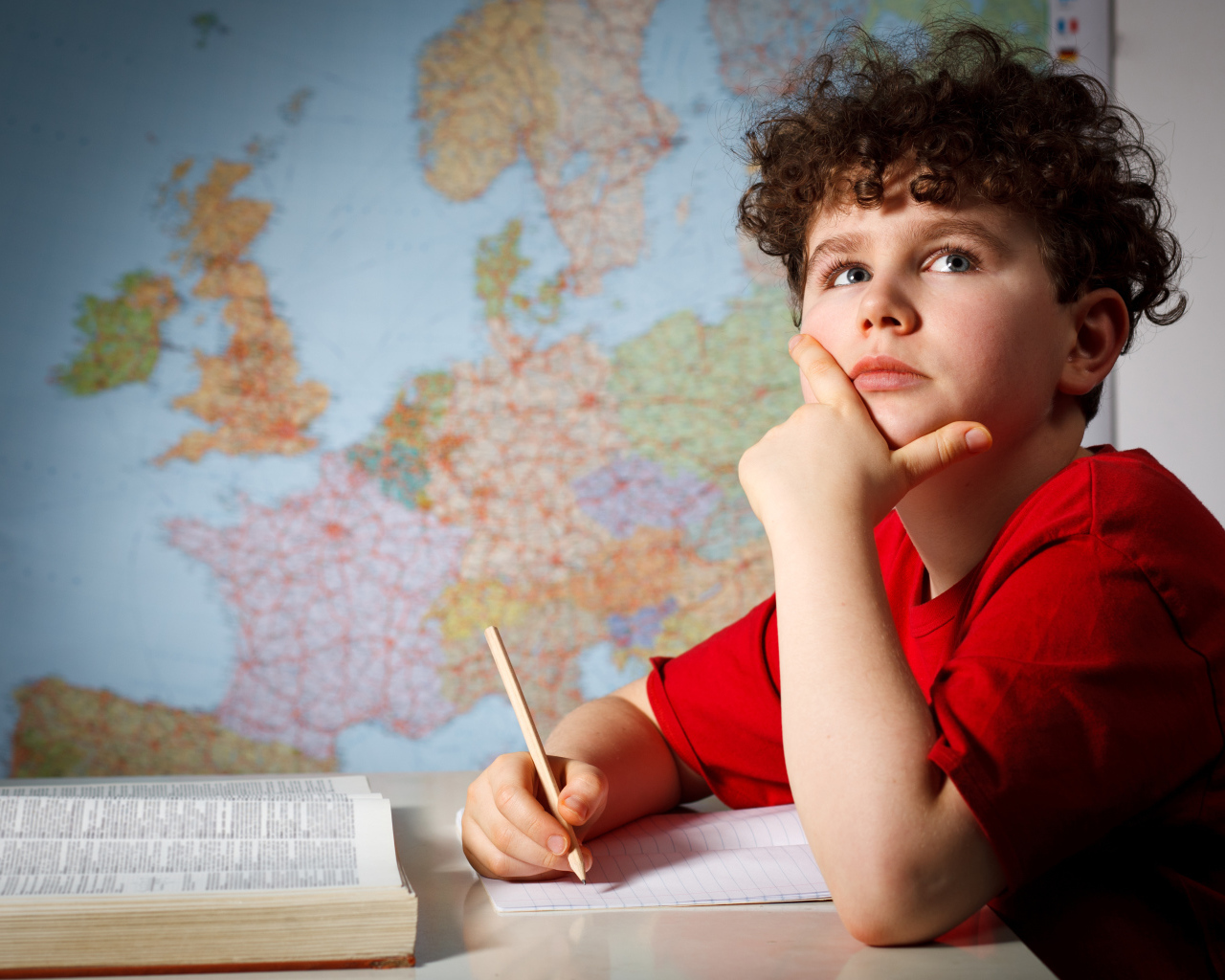 Мальчик ученик делает уроки за столом 