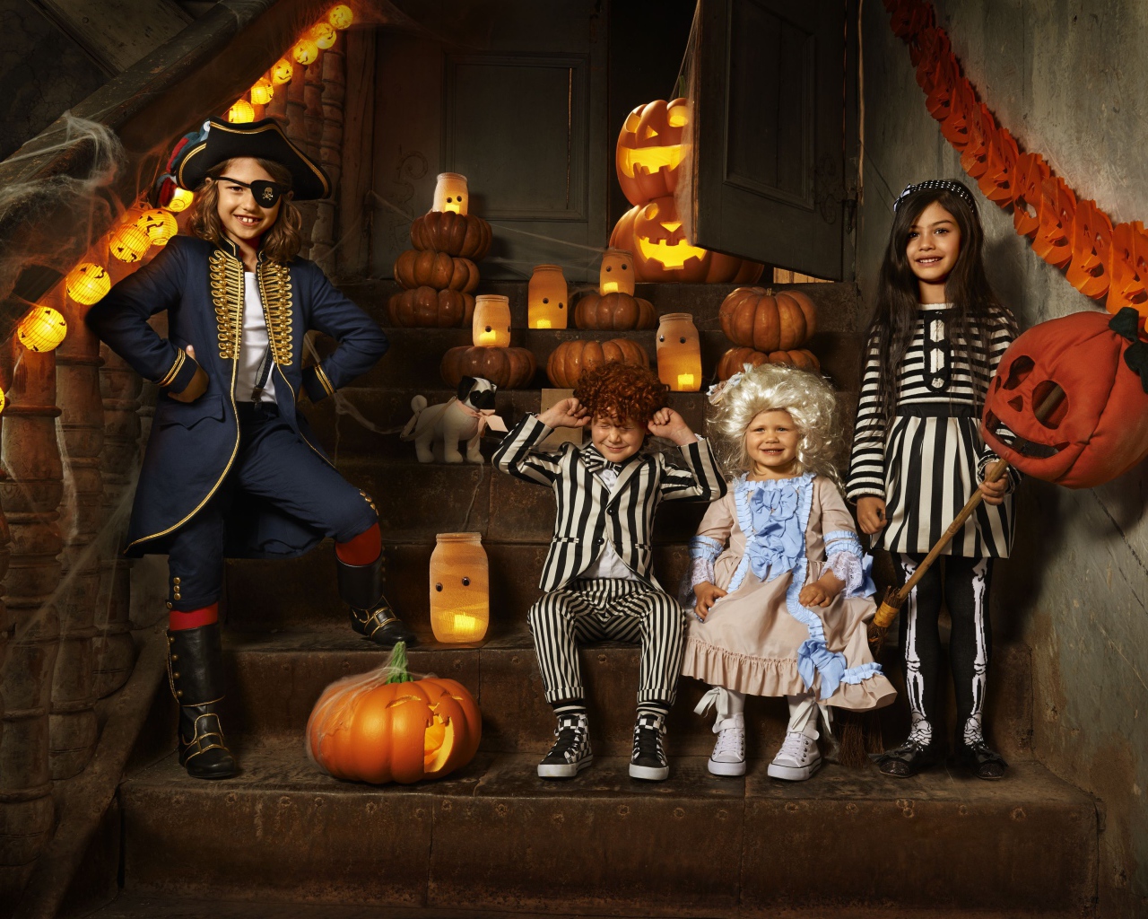 Дети в костюмах на Хэллоуин с тыквами на ступеньках