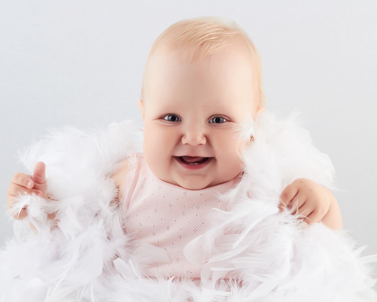 Смеющаяся маленькая девочка с перьями