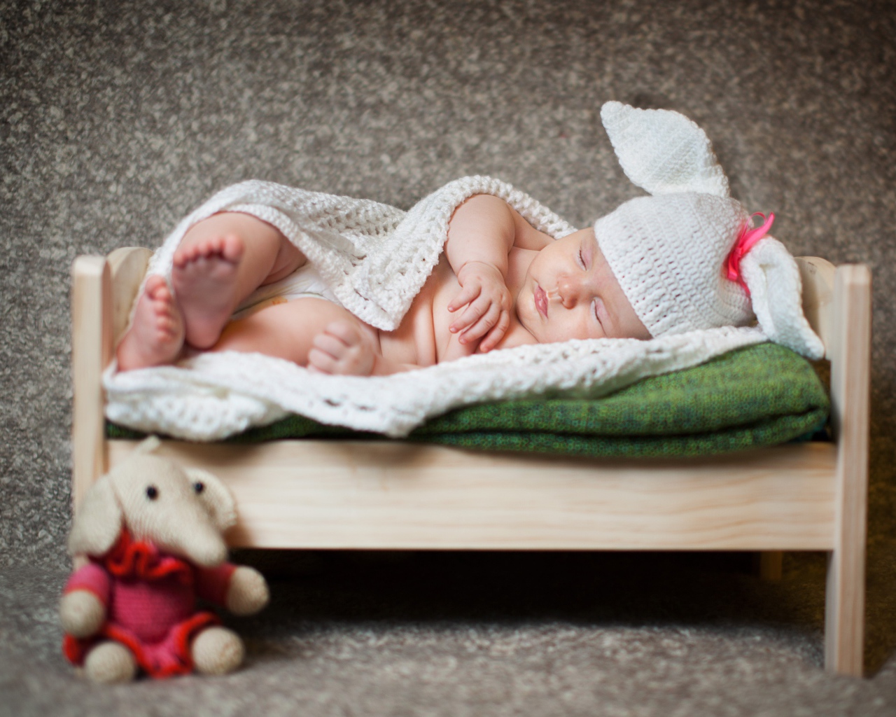 Маленький ребенок в костюме зайца на кровати 