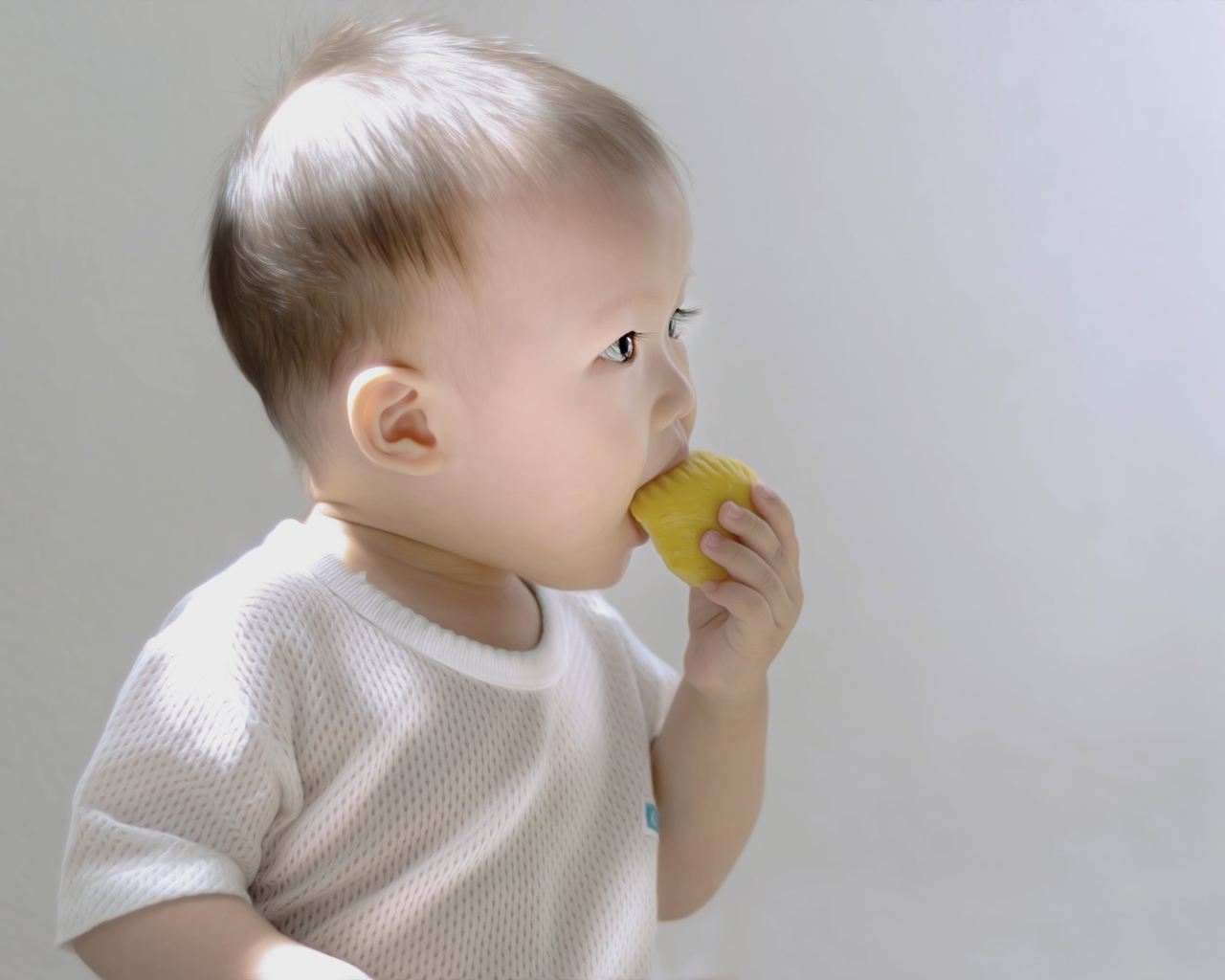 Маленький ребенок грызет игрушку на сером фоне