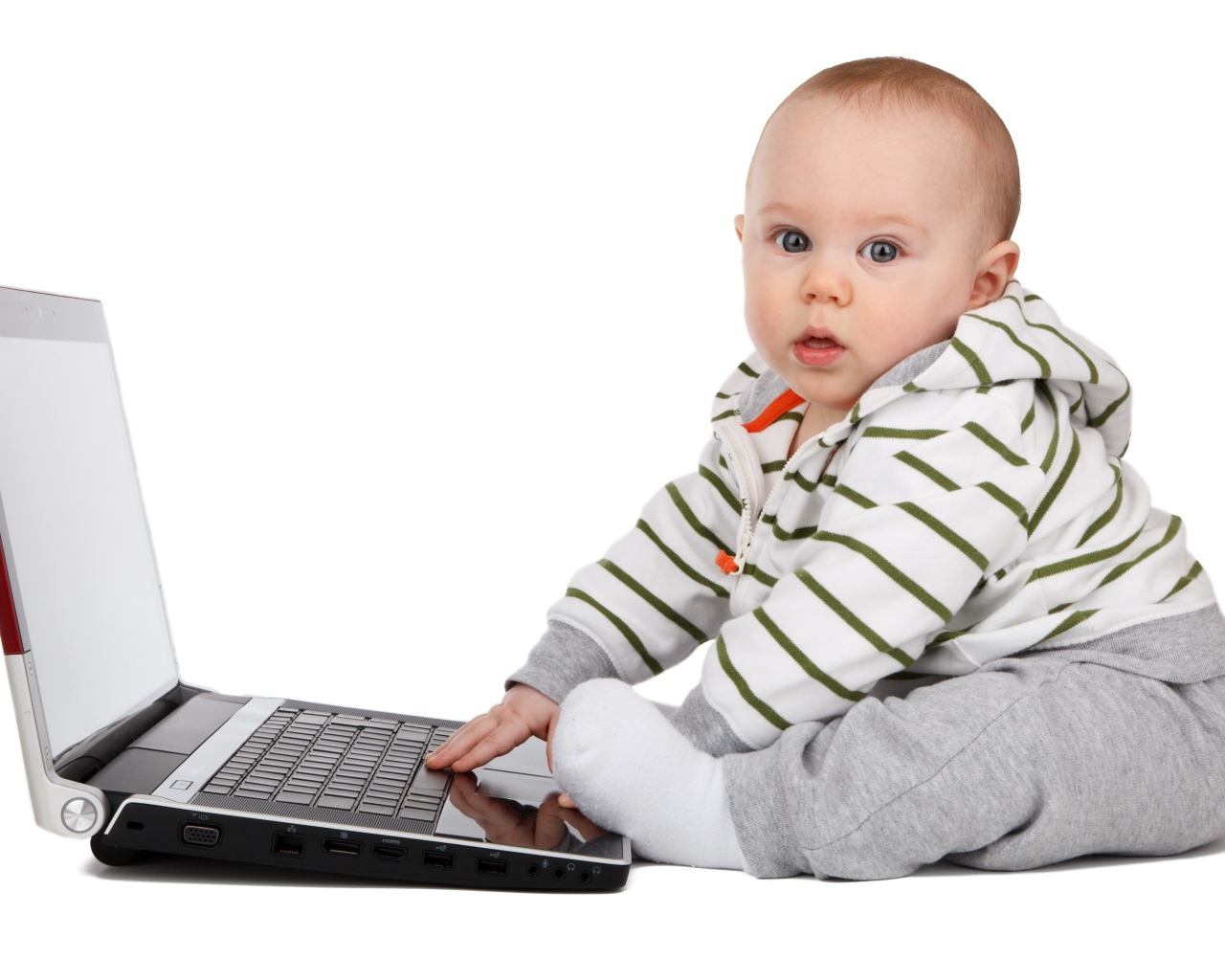 Маленький ребенок сидит с ноутбуком на белом фоне