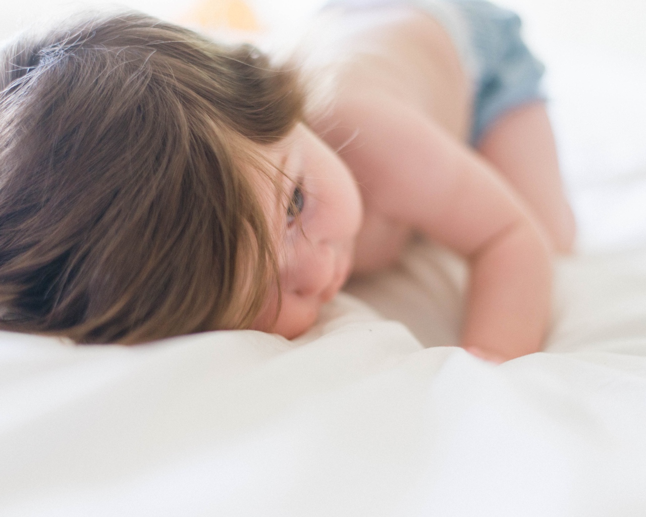Маленький ребенок с русыми волосами лежит на кровати