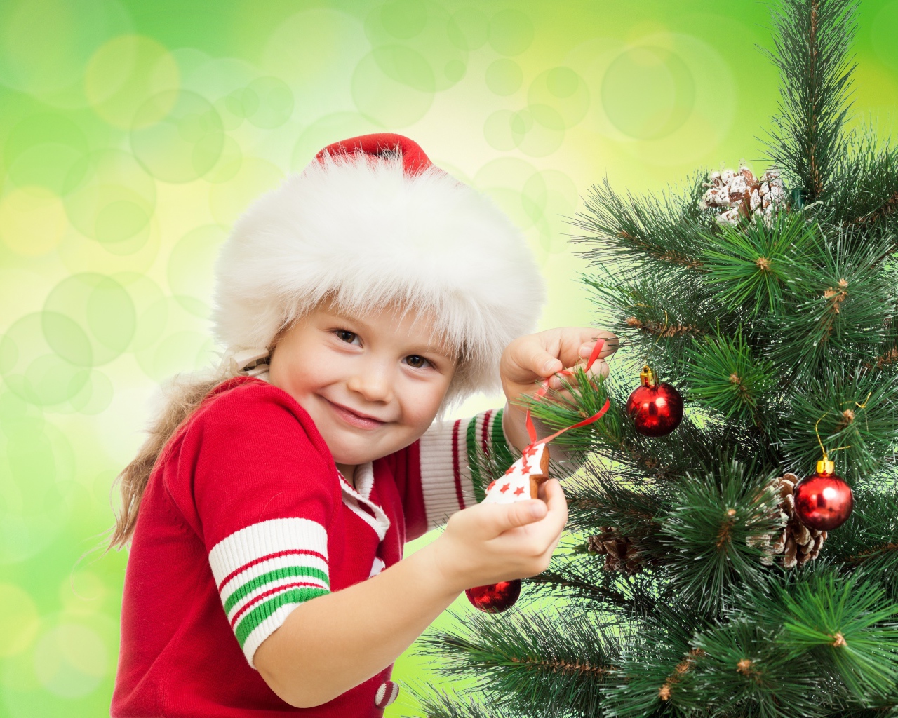 Маленькая красивая девочка наряжает елку на новый год