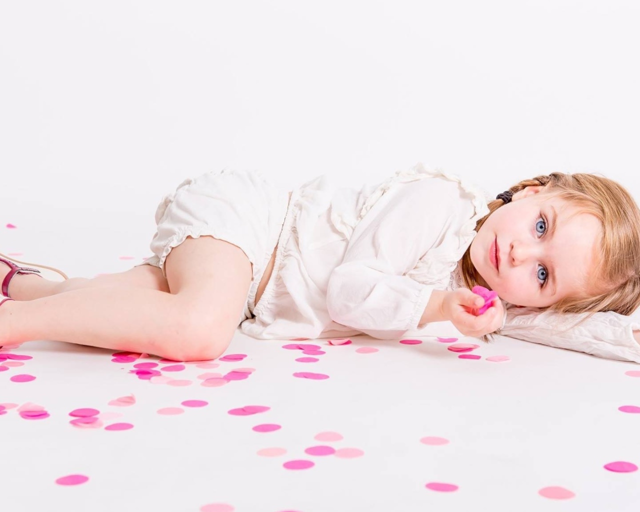 Маленькая голубоглазая девочка лежит на полу