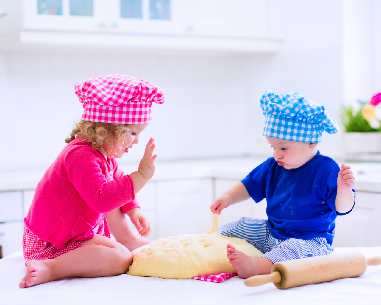 Маленькие мальчик и девочка на кухне с тестом